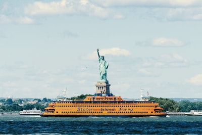 Liberty island yellow boats on the waters near the statue of liberty
